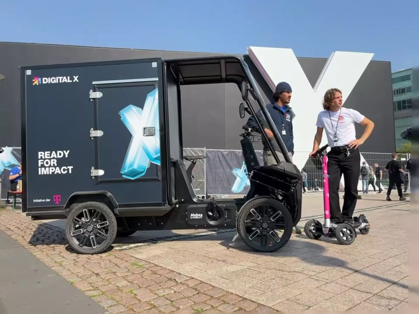 Digital X 2024: Lastenrad und E-Scooter mit Fahrern vor einem Gebäude der Digital X